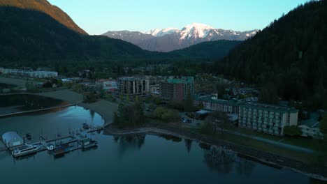 aerial shot revealing harrison hot springs at sunset on a sunny day with cheam peak in the background, british columbia, canada
