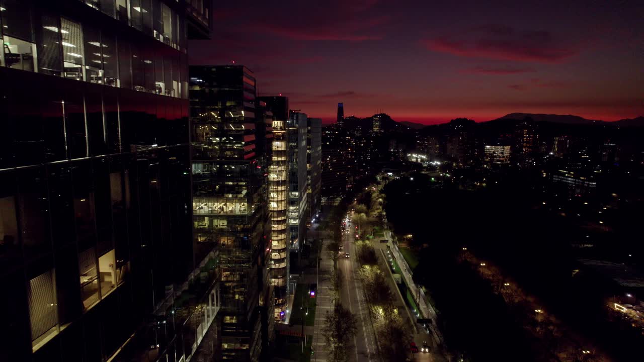 los edificios modernos de nueva las condes en santiago, chile, el centro de negocios de la ciudad, con la torre costanera en el fondo por la noche con una puesta de sol naranja.