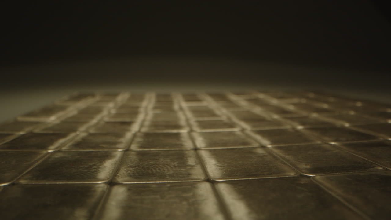 Beautiful macro dolly of reflective silver bars neatly organized in a dark room