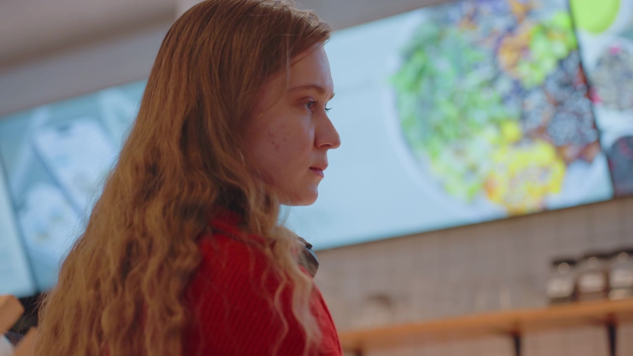 Young Woman Looking at Digital Menu Board in Cafe
