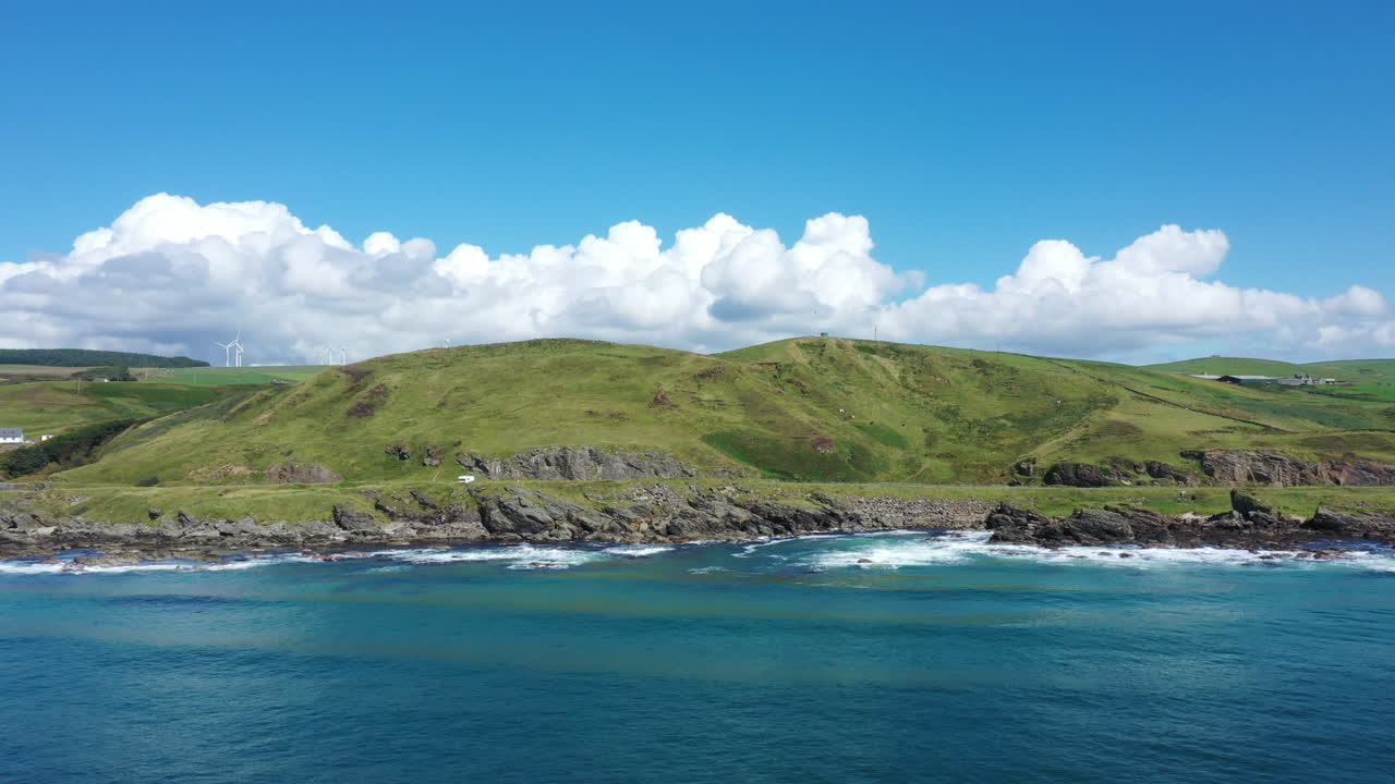 스코틀랜드 하이랜드의 바위 해안선의 공중 촬영, 밝은 은 날에 파란 바다와 초록색 언덕을 보여줍니다.
