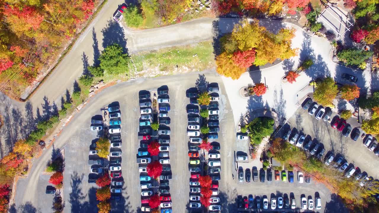 A parking lot surrounded by trees with autumn foliage in estrie, québec, aerial view