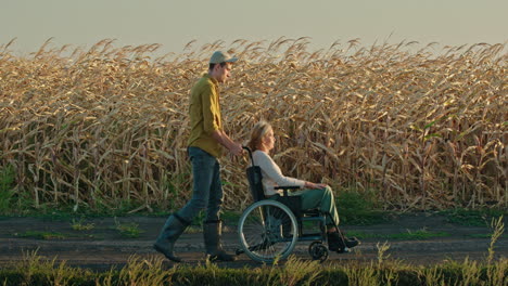 man pushing woman in wheelchair through cornfield