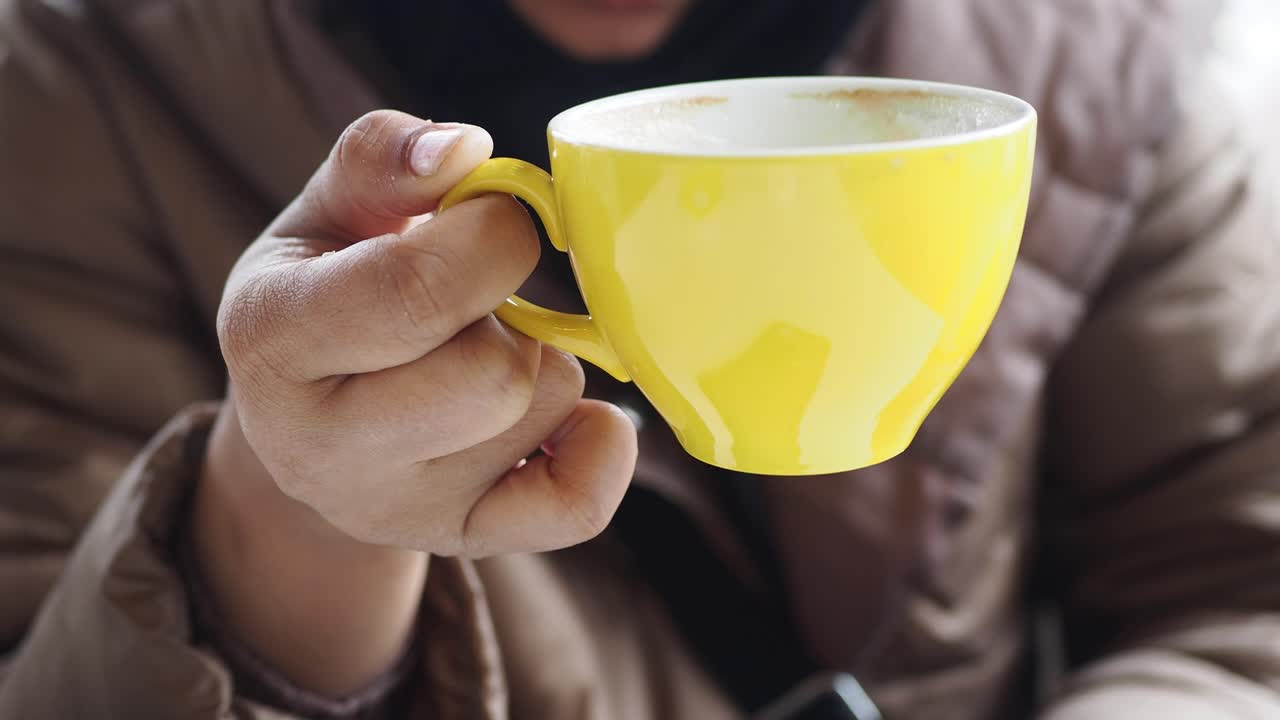 mujer sosteniendo una taza de café amarilla
