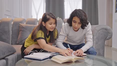 happy indian siblings studying and learning together at home