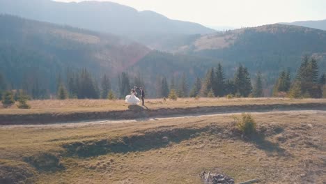 Newlyweds-dancing-on-a-high-slope-of-the-mountain.-Groom-and-bride.-Aerial-view