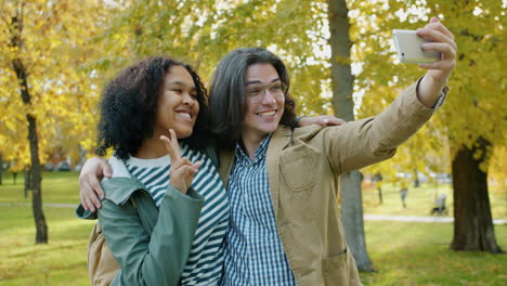 una pareja feliz tomando una selfie en el parque de otoño.