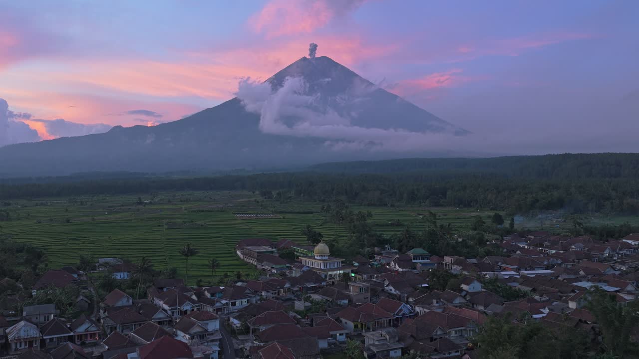 Gunung Semeru meletus saat matahari terbenam di atas sebuah desa di Jawa, Indonesia.
