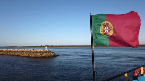 la bandera portuguesa ondea con viento fuerte en el ferry en el puerto de olhao, portugal