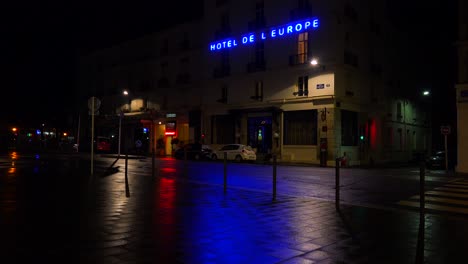 un letrero de hotel se refleja en las calles lluviosas de parís o francia con una luz en el piso de arriba 1