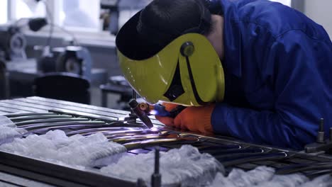 man wearing mask welding in a workshop. metal workers use manual labor. skilled welder. welder is welding the stainless steel pipes in the factory. welder industrial part in factory.