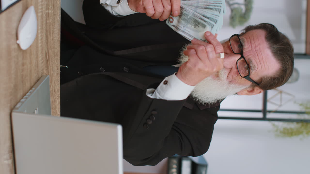 의상 을 입은 노인 이 책상 에서 현금 을 들고 있다