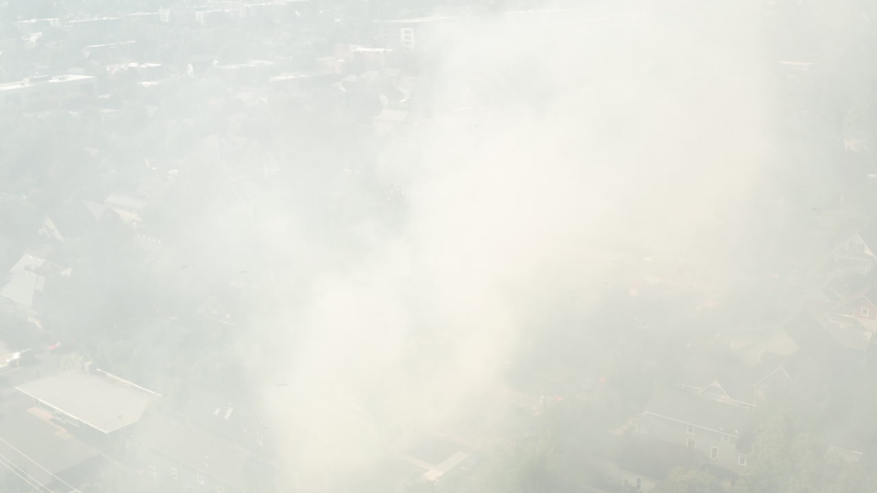 un tiro aéreo en círculo a través del humo de un incendio en la casa