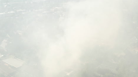 circling aerial shot through smoke from a house fire