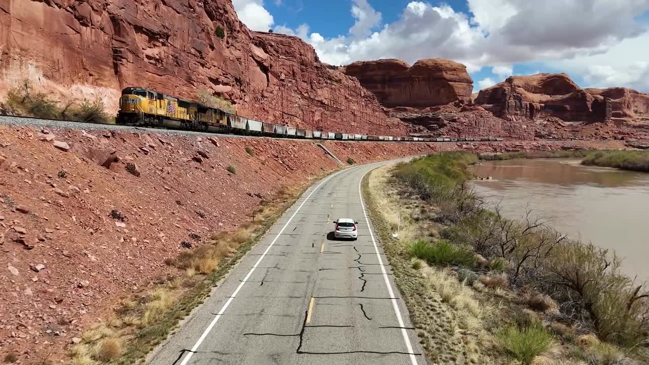 Car Driving Down Road as Train Passes in Opposite Direction, Red Cliffs, Colorado River, Moab Utah, Potash Road, Blue Skies, Sandstone Rock Formations