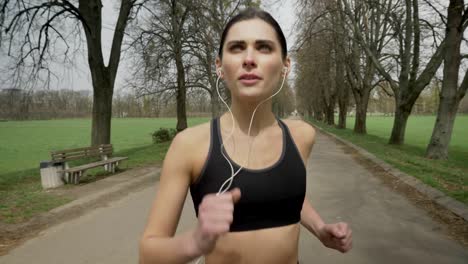 young sport girl is running with earphones in park in summer, healthy lifestyle, sport conception