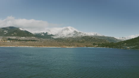 Drone-footage-of-a-road-with-cars-next-to-a-water-reservoir-in-a-snow-mountain-in-Madrid