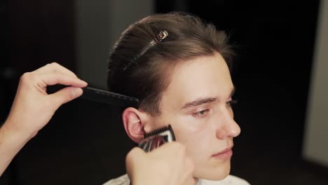 close-up portrait of a haircut with a clipper and a comb of long hair