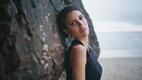 attractive girl leaning beach cliffs closeup. sexy model posing sandy seashore