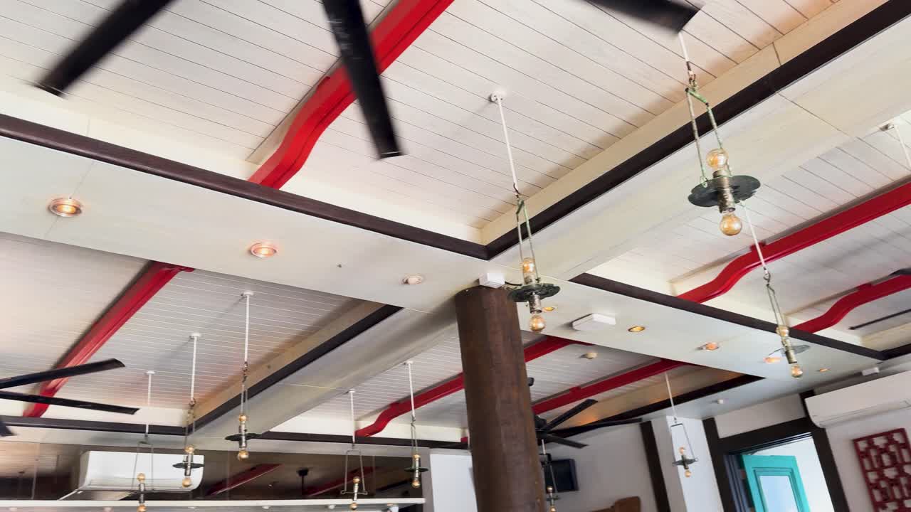 Ventilatori a soffitto in un ristorante di un resort di lusso a Phuket, Thailandia. L'illuminazione brillante, le travi in legno e il design moderno creano un'atmosfera invitante.