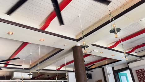 ceiling fans in a luxury resort restaurant in phuket, thailand. bright lighting, wooden beams, and modern design create an inviting atmosphere