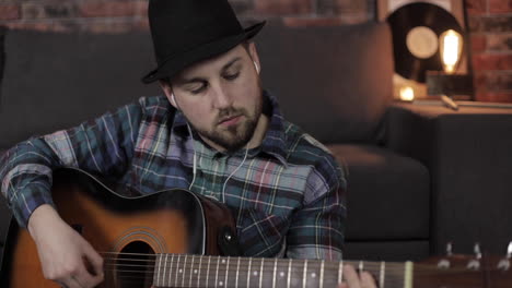 portrait of young male musician playing guitar at home