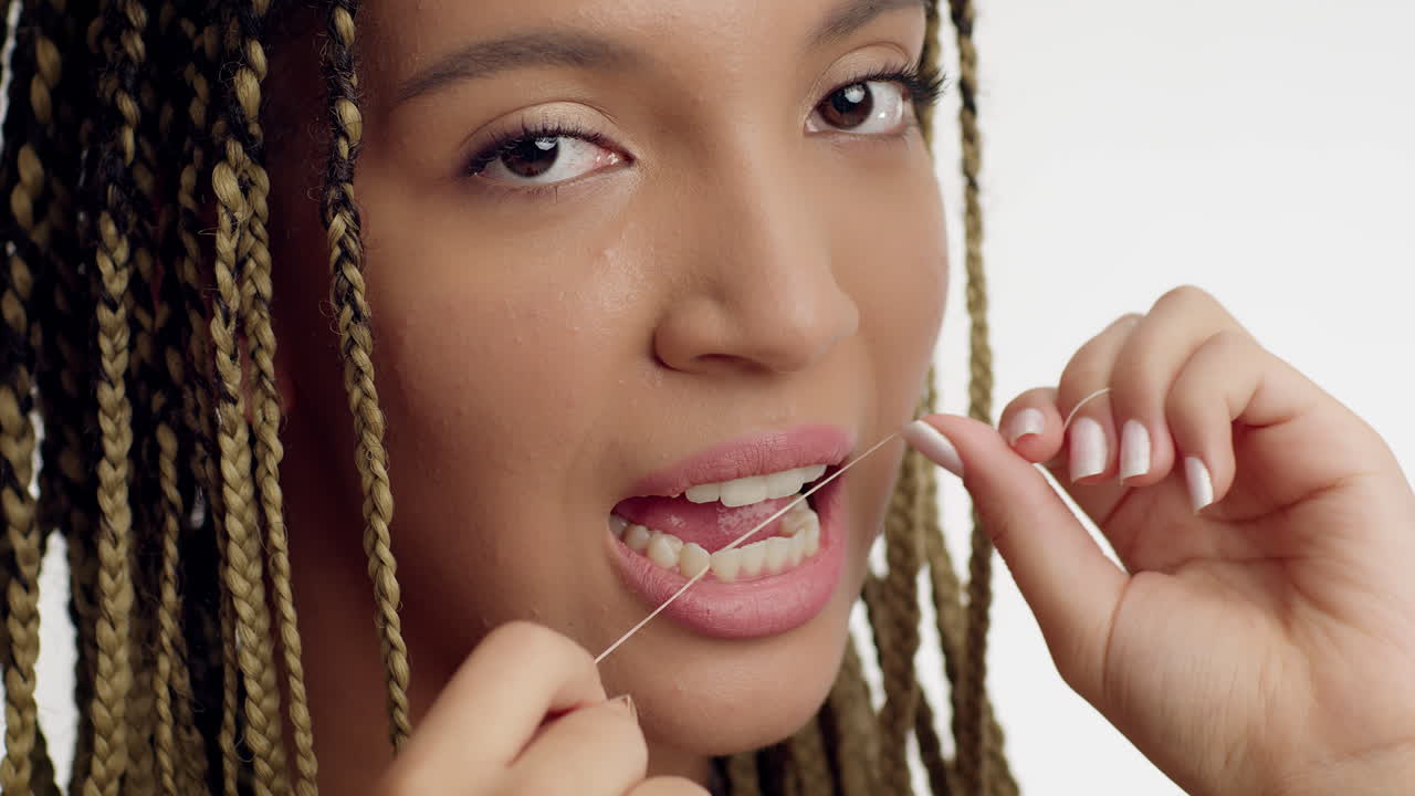 mujer lavándose los dientes con hilo dental