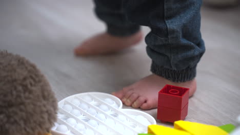 die kamera konzentriert sich auf die nackten füße eines babys, das zu hause spielt