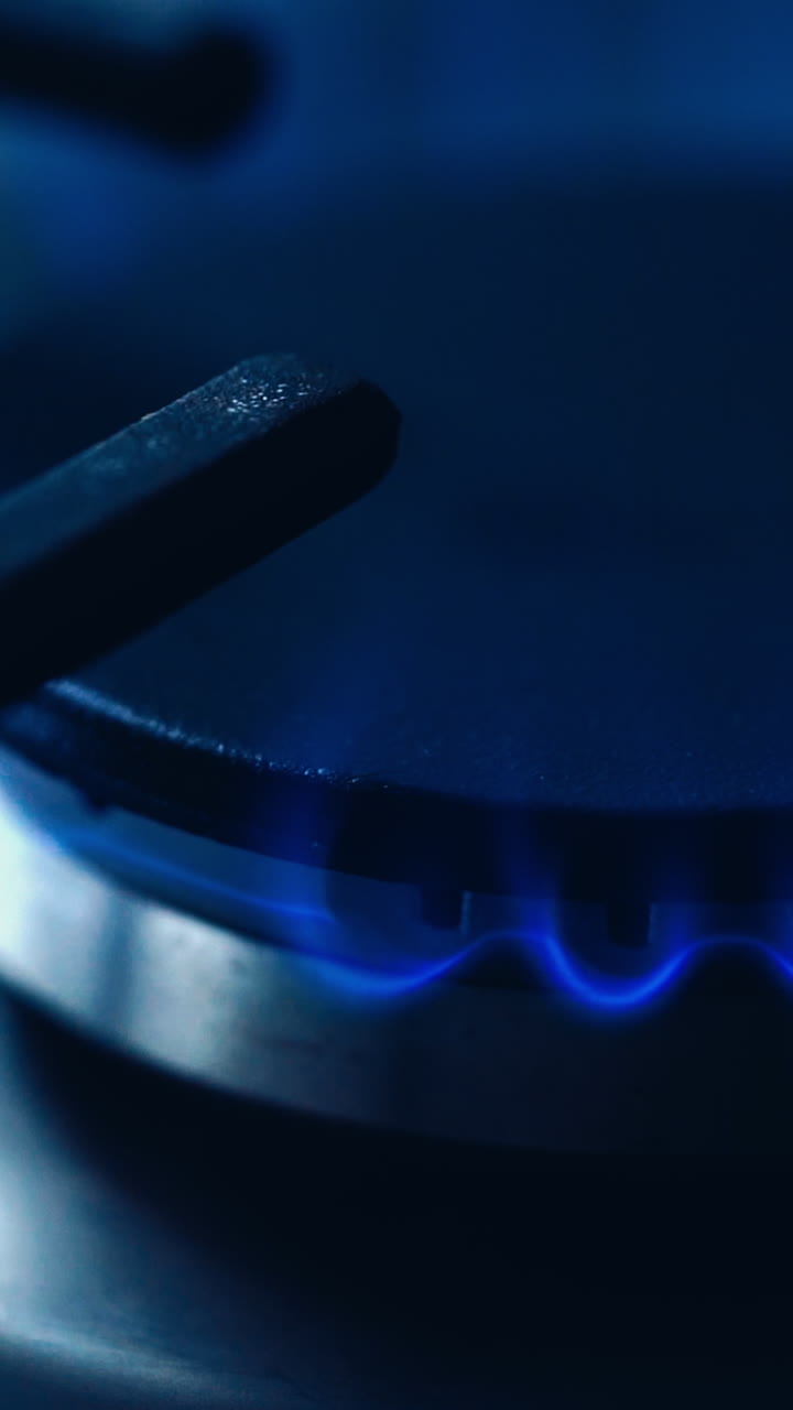 Natural gas kitchen cooker turn on and recently used. Blue and really hot flames on a gas stove. Homemade cooking concept. Circle gas hob burning ready to be use. Natural gas inflammation, close up. Vertical video