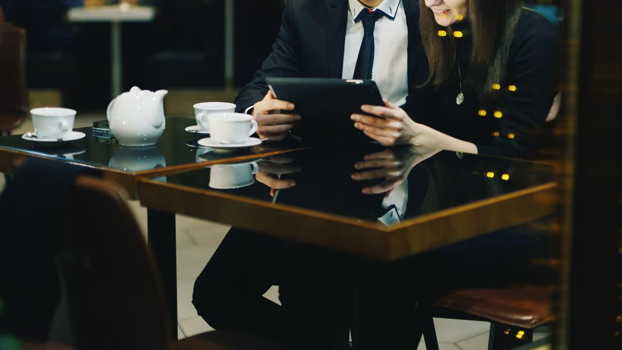 A couple in love rests in a cafe and uses a tablet 2