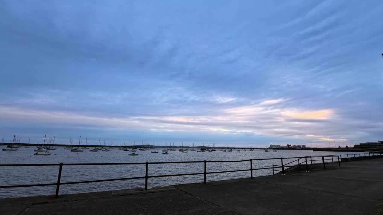 Early morning sunrise clouds time lapse passing over empty quiet Welsh waterfront harbour promenade