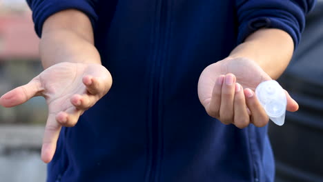 pair of hand try to squeeze hand sanitizer gel from an empty transparent bottle