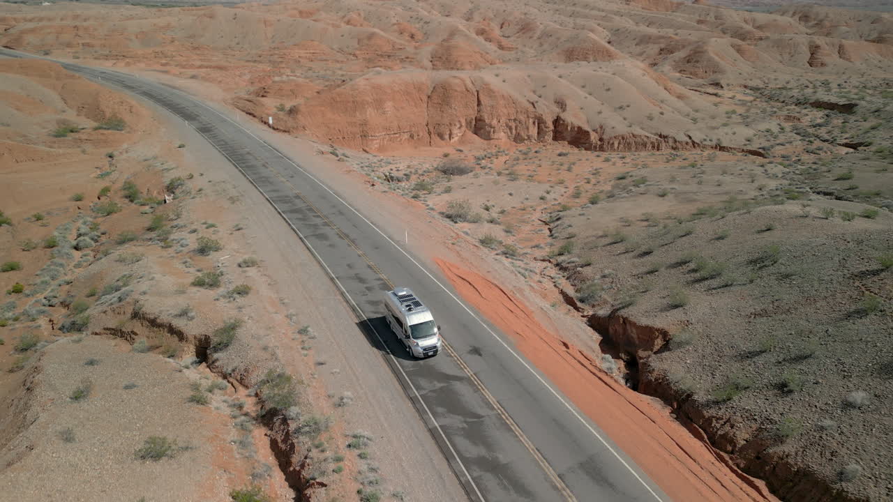 Ripresa in tracking all'indietro di un camper che percorre una strada tranquilla nel deserto