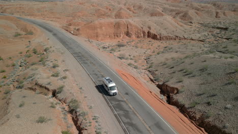 rearwards tracking shot of an rv driving along a quiet road in the desert