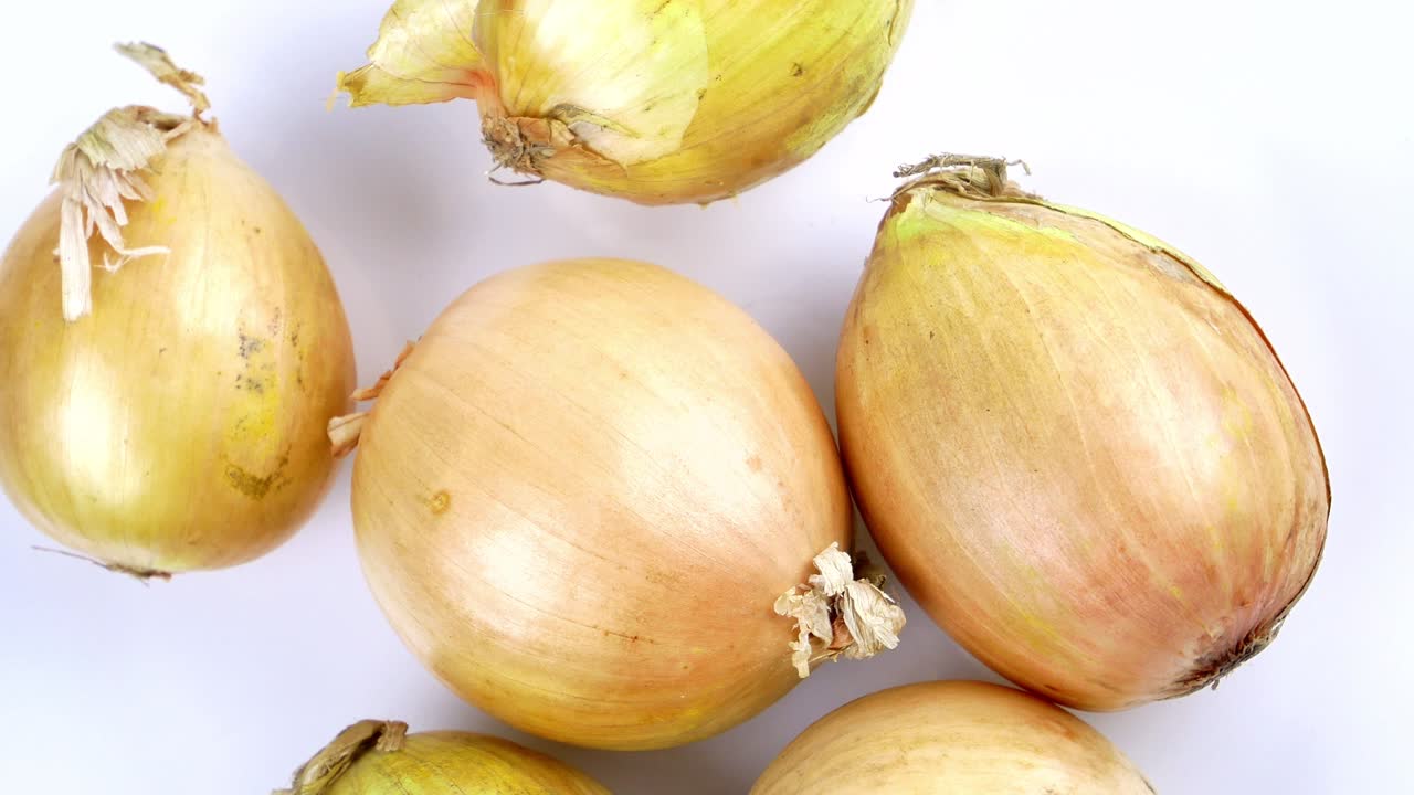 las verduras de la cebolla giran en un círculo. la cosecha de las cebollas. alimentos vegetales. alimentos vegetarianos. cocina doméstica. agricultura. menú de platos. fondo blanco. video.