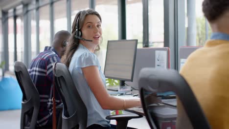 Portrait-of-happy-caucasian-businesswoman-talking-on-phone-headset-at-office