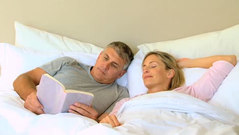 Man-reading-a-book-in-bed-with-wife