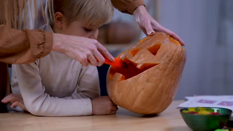 mom and child carving a halloween pumpkin