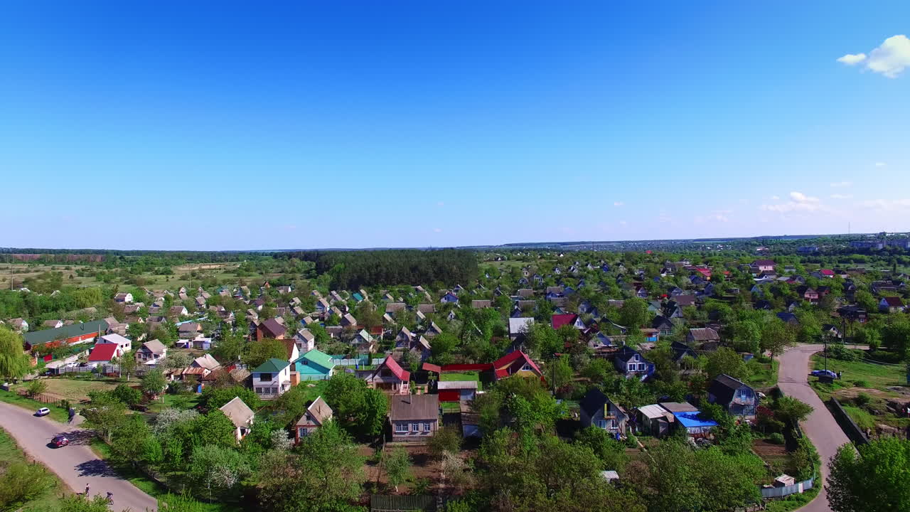 Quite big village with beautiful cottages among the green trees. Countryside with lovely nature around on sunny daytime. Blue clear sky at backdrop.