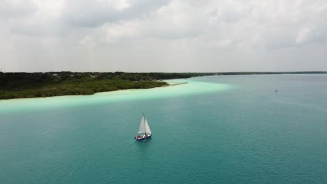 a white sail boat sailing in lake bacalar
