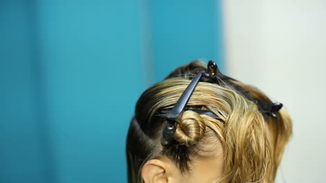 professional hairdresser dyeing hair of her client at beaty salon