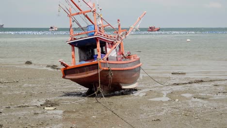 a tilt reveal shot of a moored beached squid fishing boat during low tide in thailand