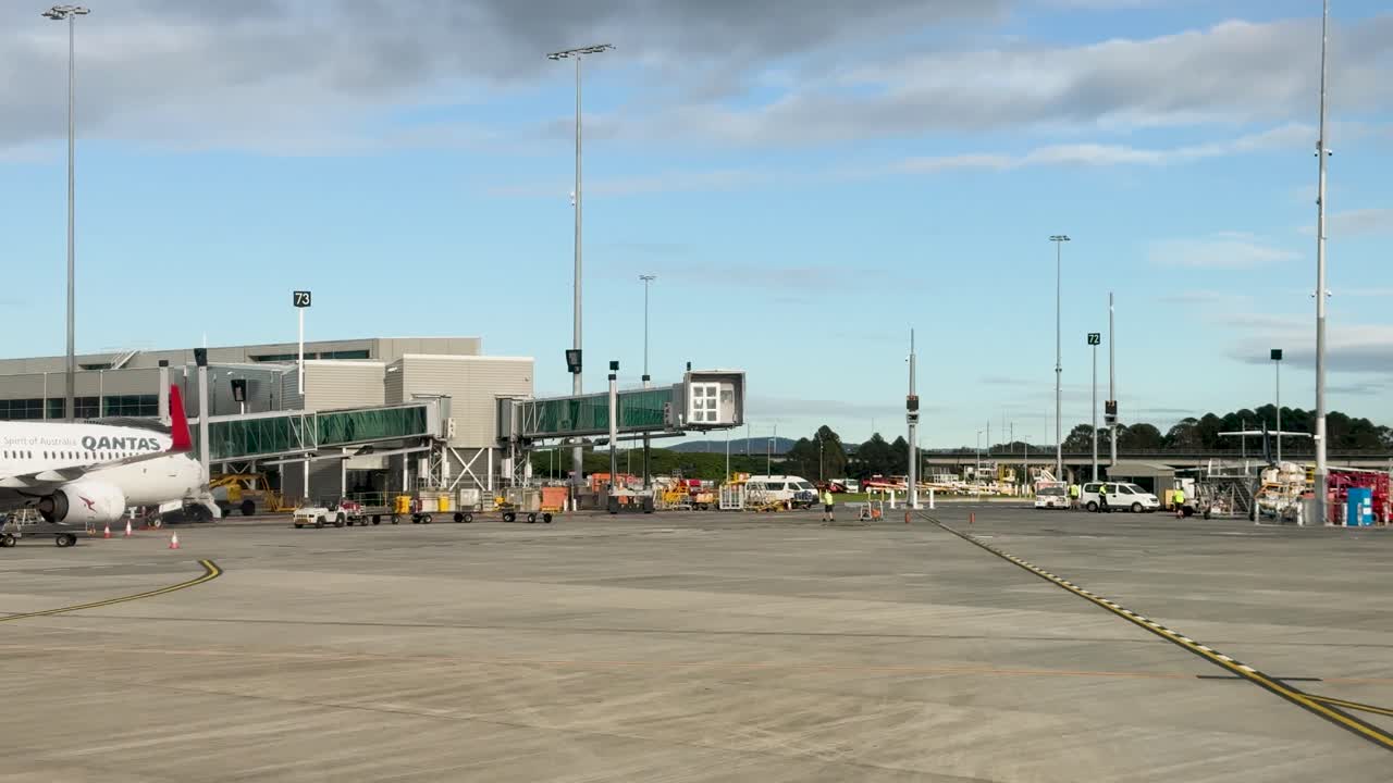 Airplanes move across a sunlit airport tarmac with clear skies, showcasing a busy and organized aviation environment