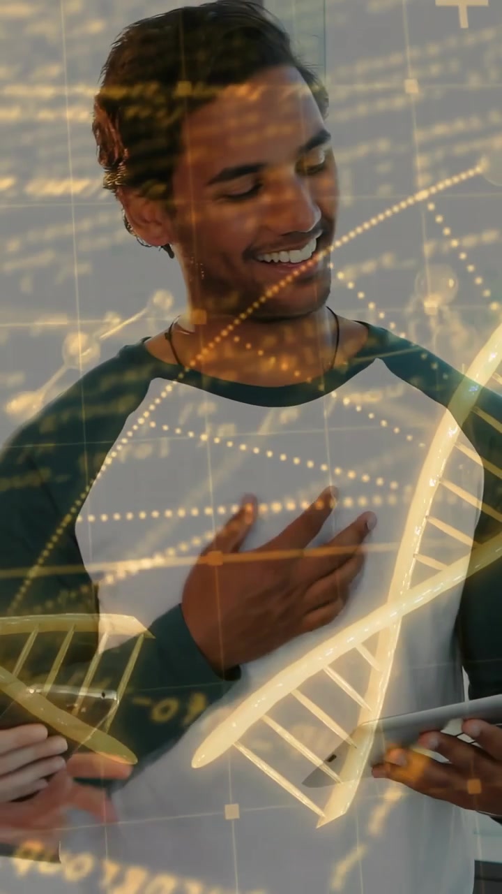 Uomo sorridente con maglietta raglan bianca che tocca un tablet, indicando un telefono nella postazione di lavoro con sovrapposizione di DNA.