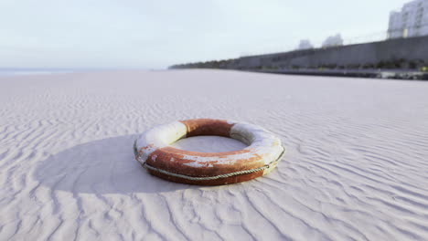lifebuoy resting on sandy beach with calm ocean in the background