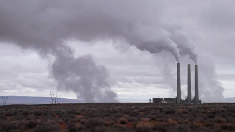 smoke rises from a factory on a barren landscape