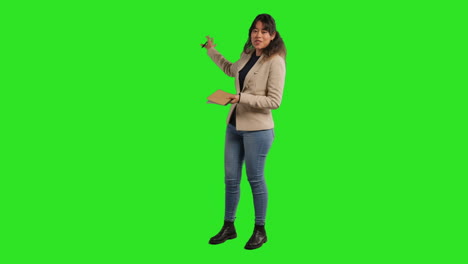 Full-Length-Studio-Portrait-Of-Female-Teacher-With-Notebook-Talking-To-Class-Standing-Against-Green-Screen-2