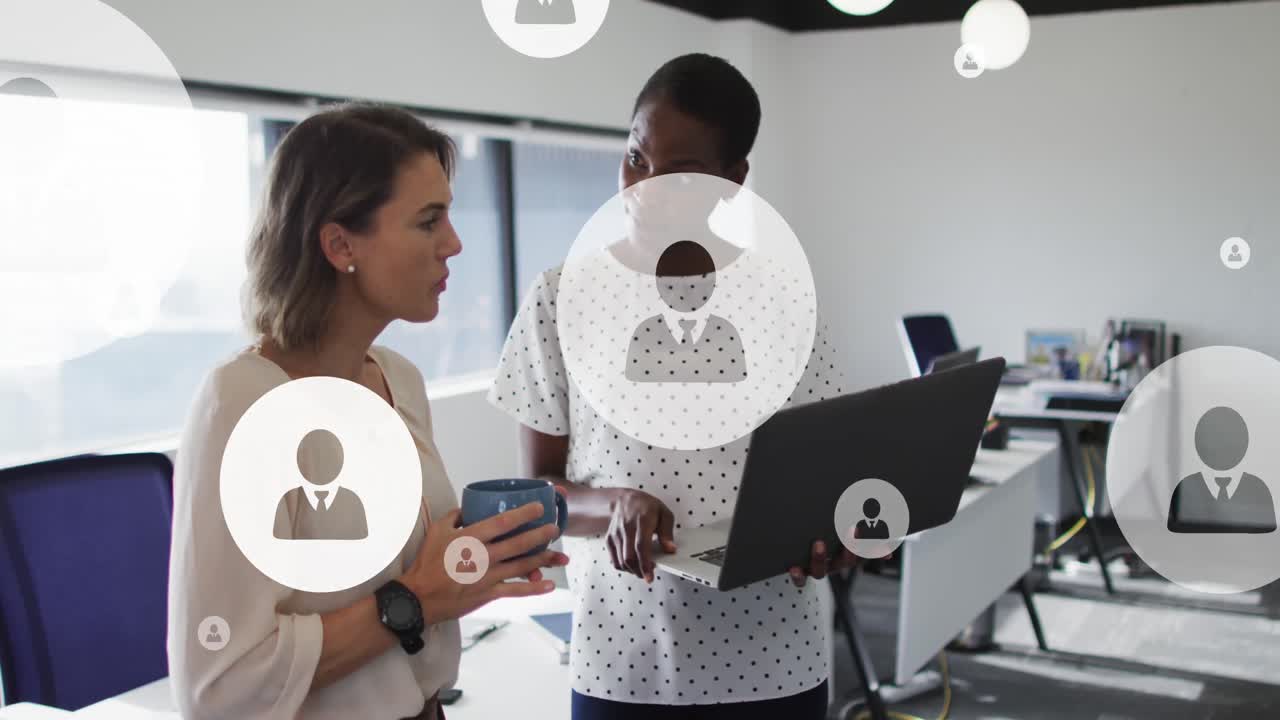 animación de iconos de perfil flotando contra dos mujeres diversas discutiendo sobre una computadora portátil en la oficina