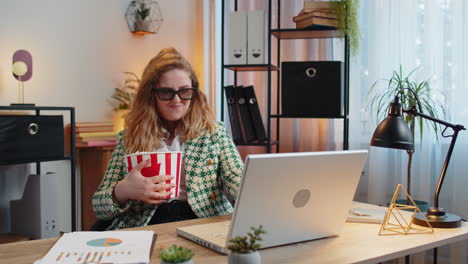 Business-woman-taking-break-from-work-wearing-3D-glasses-eating-popcorn-and-watching-movie-at-office