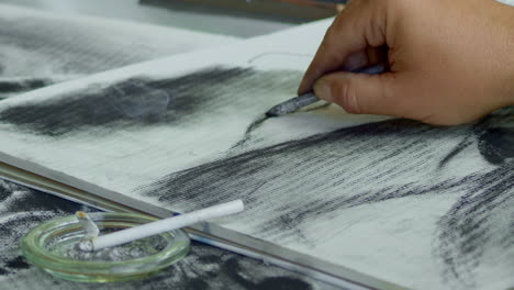 a hand with a cigarette in a decomposed charcoal drawing